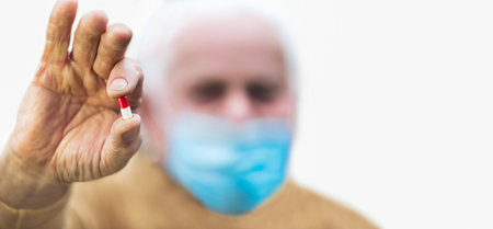 Senior man holding the new antiviral pill who can halve risk of hospitalisation.