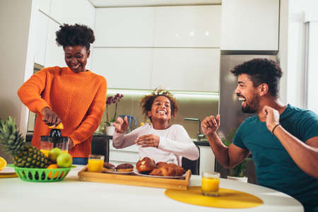 Family at home eating breakfast in kitchen togetherの写真素材