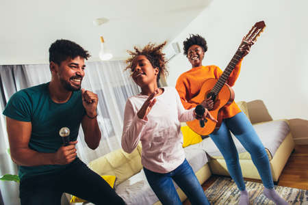 Daughter with her parents singing a favorite song on a karaoke microphoneの写真素材