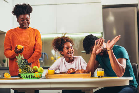 Family at home eating breakfast in kitchen togetherの写真素材
