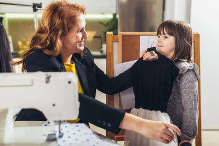 Cheerful young woman sewing with her daughter. She working at home.の写真素材