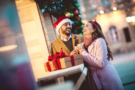 Young romantic couple holding gift box having fun outdoors in winter before Christmas.の写真素材