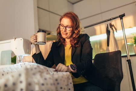 Cheerful young woman sewing. She working at home.