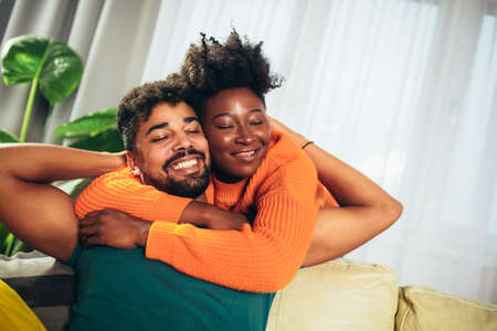 Romantic Young Couple Relaxing Sitting On Sofa Huggingの写真素材