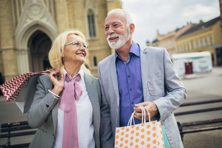 Happy senior couple walking with their shopping purchases on a sunny dayの写真素材