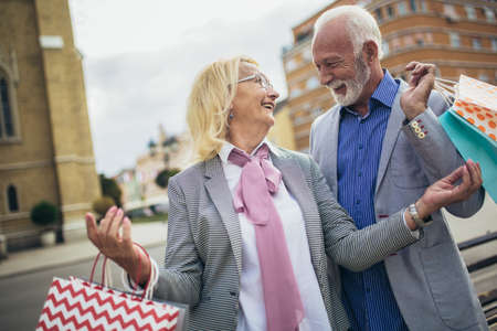 Happy senior couple walking with their shopping purchases on a sunny day