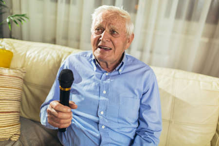 Senior man using microphone and singing karaokeの写真素材