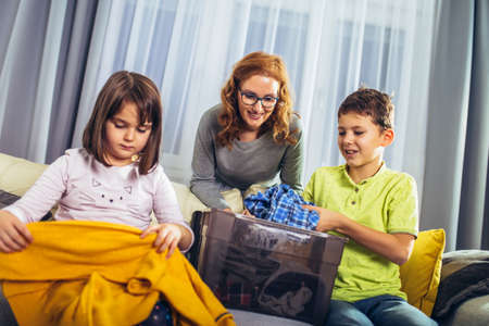Kids volunteers with they mother sorting clothes donation goods in donate charity boxesの写真素材