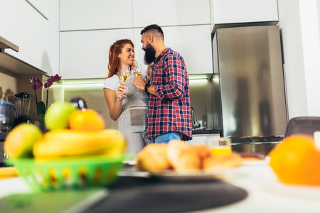 Young couple in love drinking wine in house kitchenの写真素材