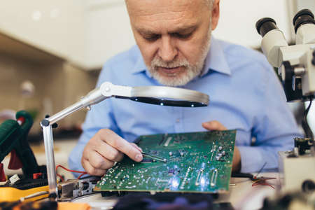 Engineer fixing broken computer motherboard. Electronic repair shop, technology development conceptの写真素材