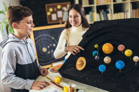 Happy school boy and girl  making a solar system for a school science project at home