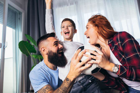 Family of fans watching a football match on TV at home
