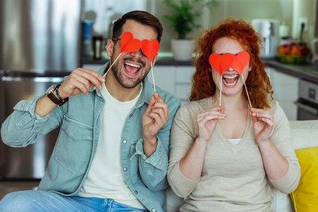 Man and woman at home holding red heart valentine in hands.の写真素材