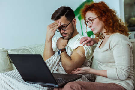 Young couple after vaccination having medical teleconsultation using laptop at home.