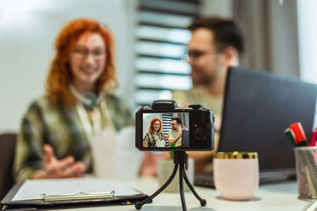Couple of bloggers broadcasting from home, using camera.