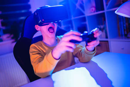 Little boy playing video game using vr glasses in the dark room