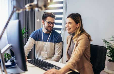 Successful young couple man and woman working on PC computer together while sitting at table at home
