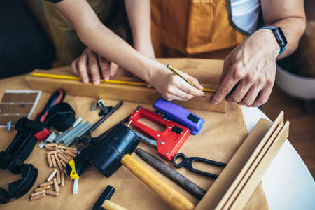 Father is teaching his son of working with wood at home. Close up