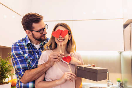 Romantic couple at home. Man giving a present to his girlfriendの写真素材