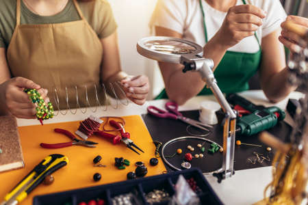 Mother and daughter accessories designers making handmade jewelry in studio workshop. Fashion, creativity and handmade concept.の写真素材