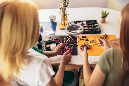 Mother and daughter accessories designers making handmade jewelry in studio workshop. Fashion,...