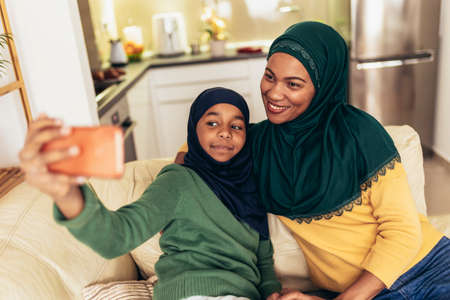 Happy muslim mother and daughter spending quality time together at home make selfie photo.の写真素材