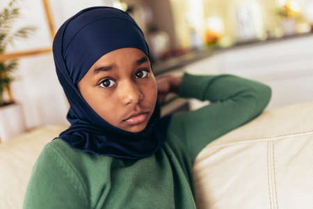 Muslim girl sitting on sofa at home.の写真素材