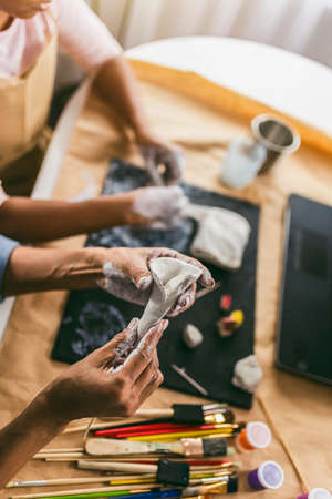 Mother and daughter spend time together and sculpting from clay at home watching online lessonsの写真素材