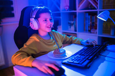 Little boy playing video game in the dark room