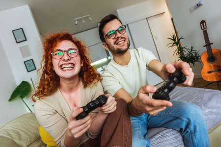 Loving couple are playing video games at home.