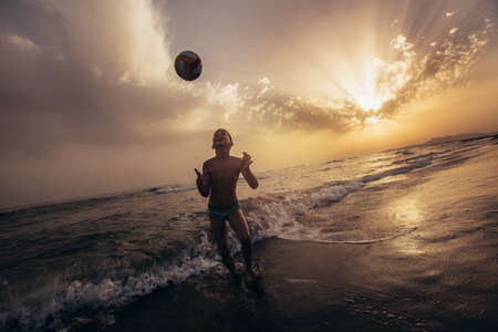 Silhouette of child playing with ball during sunset. Selective focusの写真素材