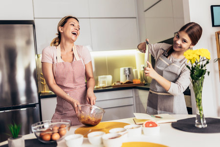 Smiling mother and daughter cooking together in the kitchenの写真素材