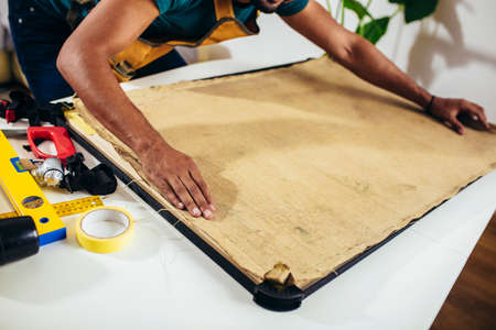Craftsman working on frame for picture at homeの写真素材