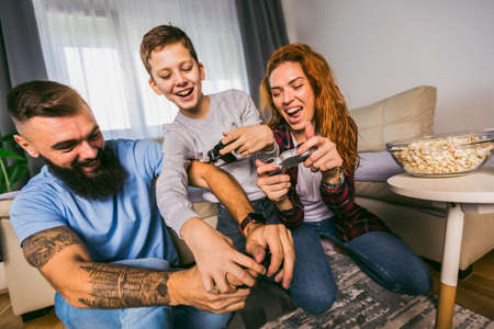 Playful family playing video games together in a living room.