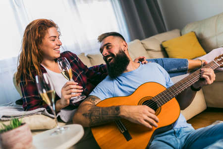 Couple is spending romantic moments together. The man is playing the guitar with his beloved girlfriend.の写真素材