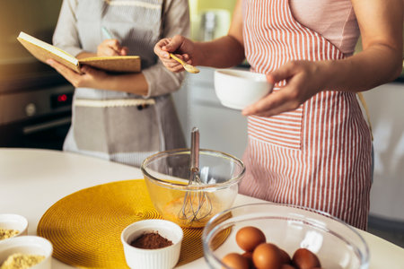 Mother and daughter cooking together in the kitchen, close up.の写真素材