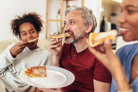 Happy family sharing pizza together at homeの写真素材