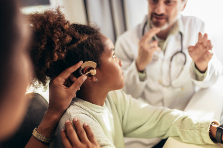 Smiling deaf african american girl with ear implant at doctor's office.の写真素材