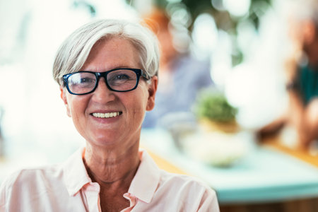 Lovely middle-aged woman with smiling sitting on a chair at home looking at the camera with friends...