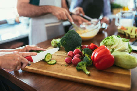 Group of senior friends at dinner party at home, cooking. Close up.の写真素材