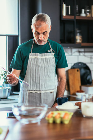 Mature handsome man cooking in home kitchenの写真素材