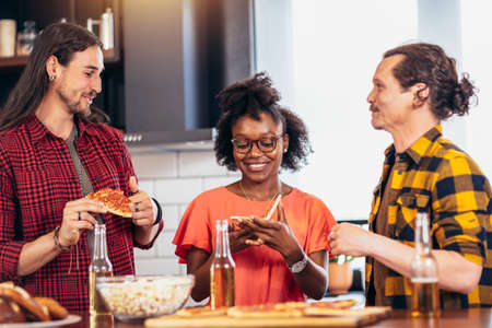 Group of friends having party at home, eating pizza and having fun.