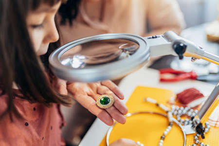 Mother and little preschooler daughters have fun making bracelets at home togetherの写真素材