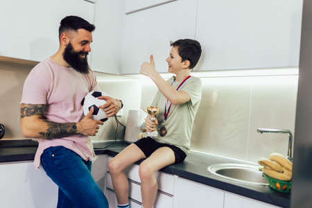 Proud father feel so excited to see his son medal and trophy in his hand after football tournament.の写真素材