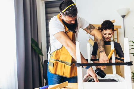Cheerful young male carpenter and his son working in workshop