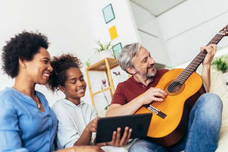 Man singing and playing guitar for his daughter and his wife.の写真素材