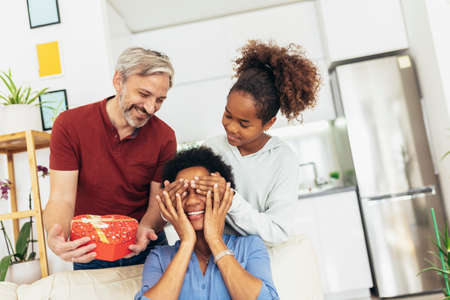 Father and daughter congratulate mother on holiday and give gift boxの写真素材