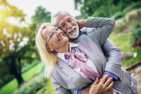 Senior active caucasian couple hugging looks happy in the park in the afternoonの写真素材