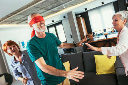 Happy middle aged friends playing hide and seek at homeの写真素材