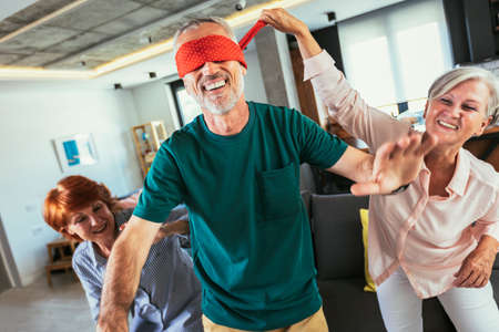 Happy middle aged friends playing hide and seek at homeの写真素材